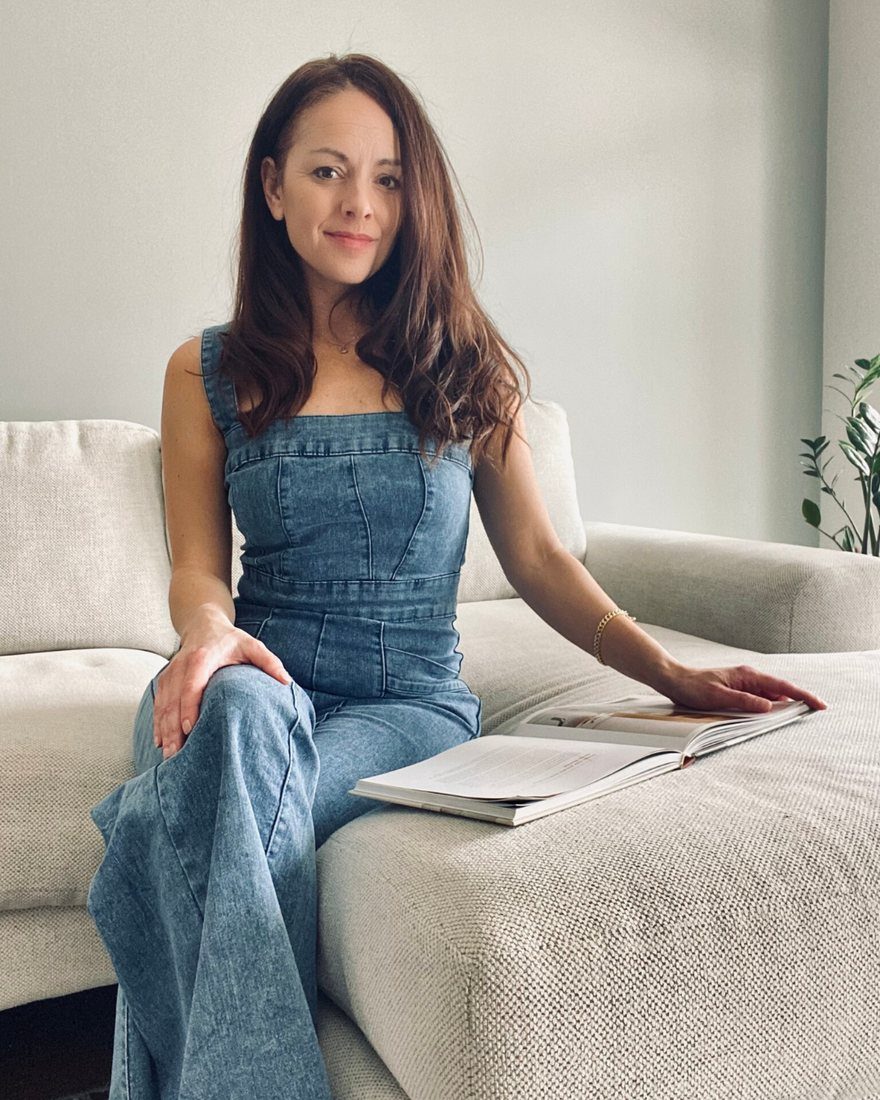 Lia, founder of Tidy by Nature, sitting on a sofa with a book.