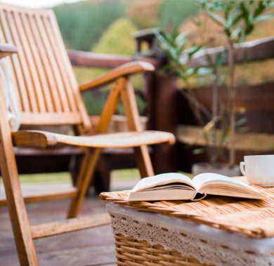 A wooden chair and a book on a basket on a terrace on a sunny day in autumn. An empty wooden chair and a book on a basket on a terrace on a sunny day in autumn.